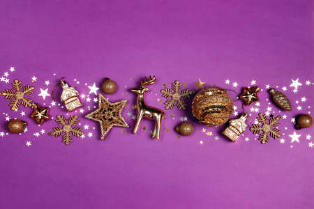 Gold Christmas composition made of many different shiny decorations on a purple background. Copy space, top view.の写真素材