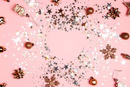 Golden glittering Christmas frame with decorations and sparkling sequins on pink background. Festive luxury background.の写真素材