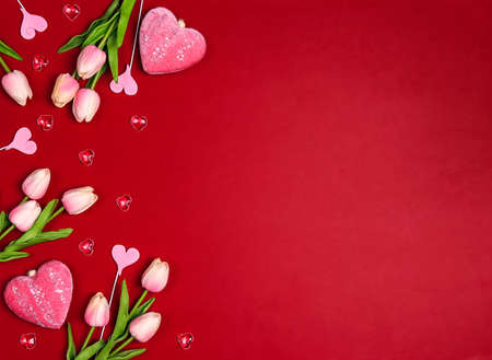 Floral border with tulips flowers and hearts on red background. Copy space, flat lay, top view.