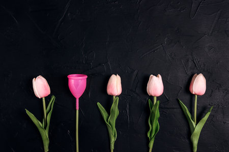 Tulips with menstrual cup as a flower on black background. Eco-friendly reusable silicone, ecological alternative, zero waste concept.の写真素材