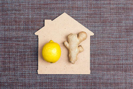 Fresh ginger root and lemon fruit with house symbol on a brown napkin. Natural medicine, anti-flu...