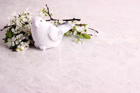 Light marble background with apple blossom branches and decorative bird. Copy space for text.