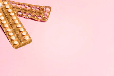Female oral contraceptive pills empty and full blister on a pink background. Female contraceptive hormonal birth control pills. The concept of pregnancy planning. Copy space, flat lay.の写真素材
