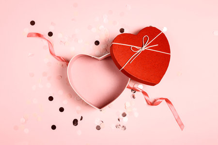 Top view of an open empty red heart shaped box on pink confetti background for your products. Happy Valentine's Day, Women's Day, Mother's Day, Birthday.の写真素材