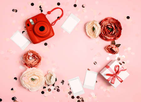 Modern instant camera with blank instant photos, peony flowers and gift box on pastel confetti pink background. Flat lay, top view with place for your images and text.の写真素材