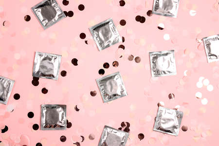 Package of condoms on a pink confetti background. The concept of safe sex and reproductive health.の写真素材