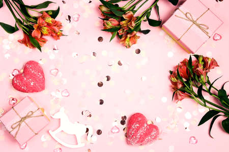 Girly frame made of flowers, gifts and hearts on a pink background. Invitation, birthday, party, baby shower concept.の写真素材