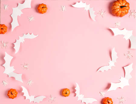 Halloween pink background with white bats, spiders and pumpkins. Flat lay, top view frame with copy space.の写真素材