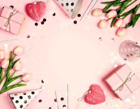 Girly birthday frame with flowers, gifts, hearts and caps on a pink background. Invitation, birthday, party, baby shower concept.の写真素材