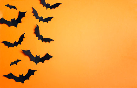 Halloween paper black bats on an orange background. Flat lay, top view, copy spaceの写真素材
