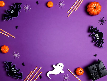 Halloween purple background with bats, spiders, pumpkins and gift. Flat lay, top view frame with copy space.の写真素材