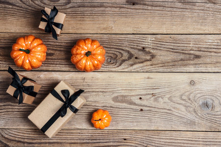 Gift boxes with black ribbons and pumpkin on the old wooden boards. Top view Halloween background with copy space.の写真素材