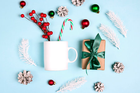 White coffee mug with Christmas decorations on a blue background. White ceramic mug mockup for design, quote, brand or logo.の写真素材