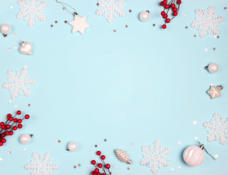Christmas frame of white decorations and red berries on blue background. Christmas, winter, new year concept with copy space.の写真素材