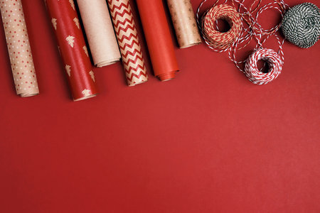 Christmas preparations with paper roll and decorative ropes on red background. TChristmas and New...
