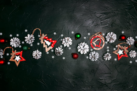 Christmas black background with snow painted cones and decorations. Copy space, top view.の写真素材