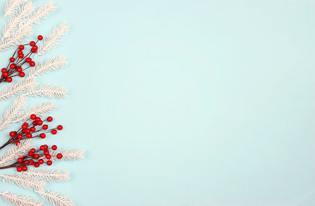 Christmas border with white spruce branches and red berries on blue background. Christmas, winter, new year concept with copy space.の写真素材