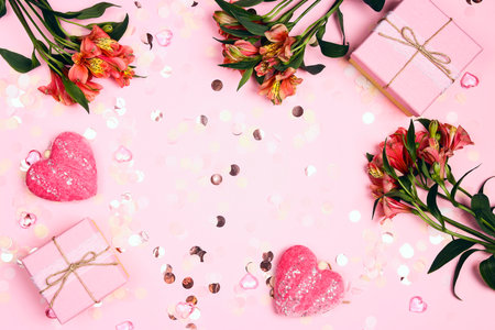 Romantic frame of Alstroemeria flowers with confetti and gifts on pink background. Holiday, birthday, Valentine's day concept. Flat lay, top view, copy space.の写真素材