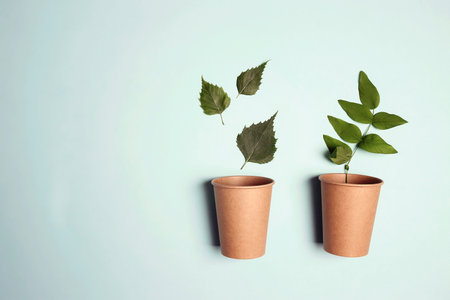 Eco-friendly coffee to go cups with green leaves on blue background. Recycled kraft paper packaging, environmentally friendly, disposable and zero waste concept.の写真素材