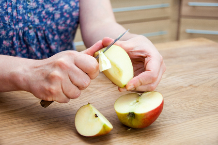 Hands peeling a cooking apple on a wooden boardの写真素材