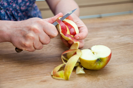 Hands peeling a cooking apple on a wooden boardの写真素材