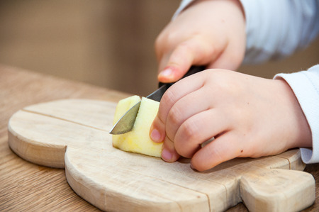 Child cutting an apple on wooden tableの写真素材