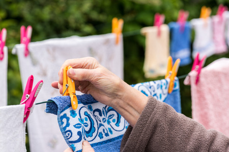 Old woman hanging laundry outdoorの写真素材