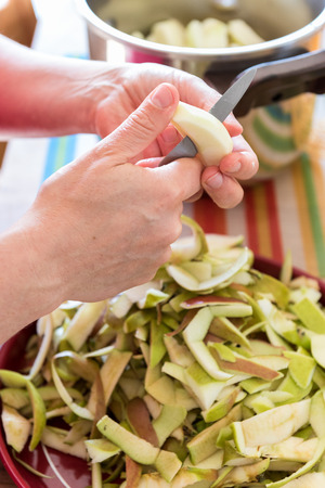 Woman Hand's peeling a cooking apple in a kitchenの写真素材