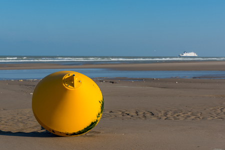Yellow buoy on the beach , with blue skyの写真素材