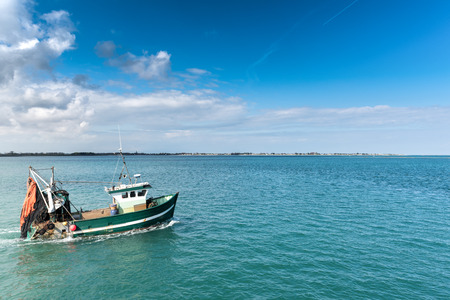 Fishing boat leaving the harbor of Barfleur, France,