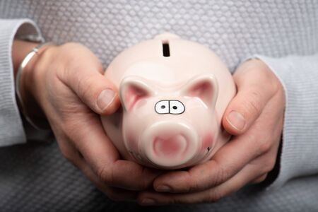 Woman holding in her hands a piggy bankの写真素材