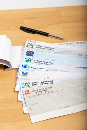Paris, France - November 18, 2019 : Checks of different french banks set on a wooden desk. France is the European country where checks are most usedのeditorial素材