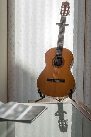 Wooden guitar in front of a windowの写真素材