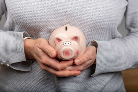 Woman holding in her hands a piggy bankの写真素材