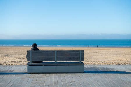 Retired man looking at the sea sitting on a benchの写真素材