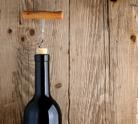 Bottle of wine with corkscrew on wooden backgroundの写真素材