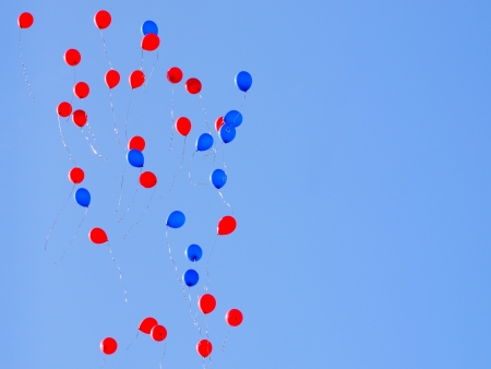 Colorful balloons flying in blue skyの写真素材
