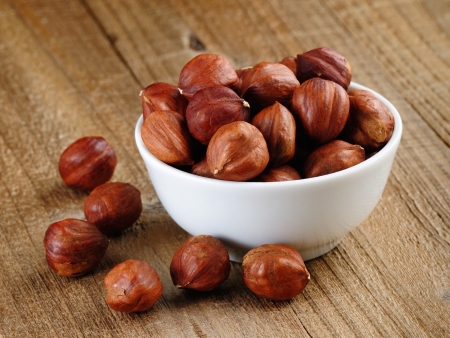 Hazelnuts in bowl on wooden tableの写真素材