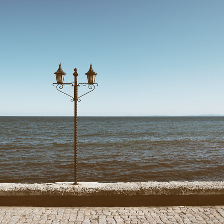 Old lantern on sea background in retro styleの写真素材