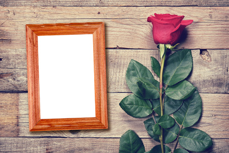 Vintage rose and blank photo frame on old wooden backgroundの写真素材
