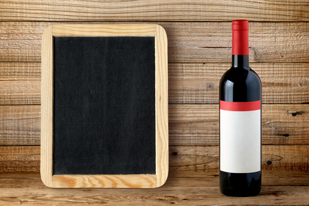 Bottle of red wine and blank blackboard on wooden backgroundの写真素材