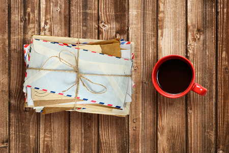 Pile of old envelopes and coffee cup on wooden table top viewの写真素材