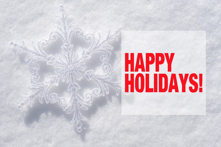 Snowflake christmas decoration and Happy holidays text on snow backgroundの写真素材