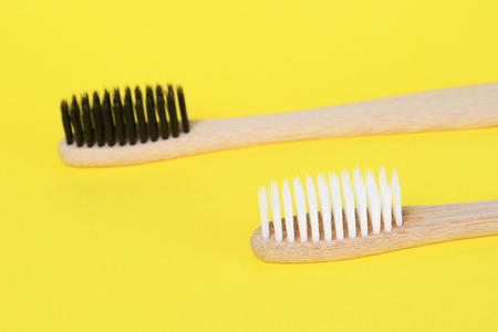 Natural bamboo toothbrushes on yellow background