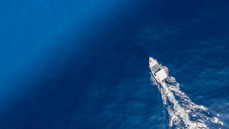 Top view of a white boat sailing in the blue sea