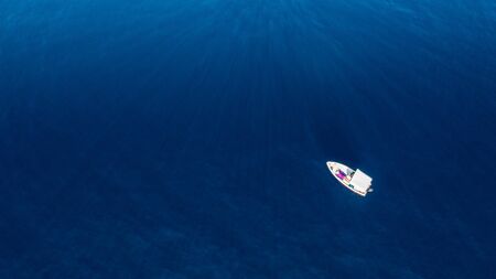 Top view of a white boat sailing in the blue sea. Young woman in pink lying with large hat in relax.の写真素材