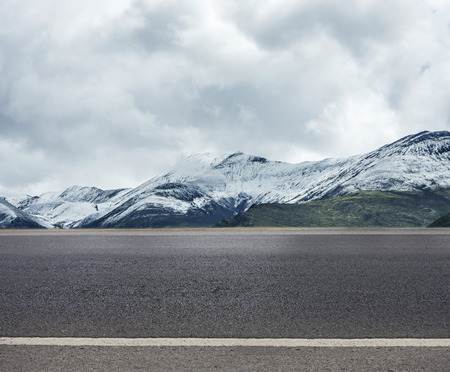 Empty highway asphalt road and beautiful snow mountain landscapeの写真素材