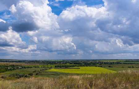 Summer landscape with green grass, village, fields and beautiful clouds, Donbassの写真素材