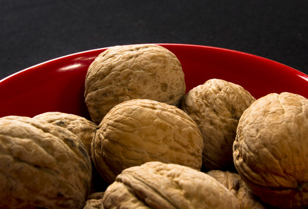 walnuts in red plate on black background