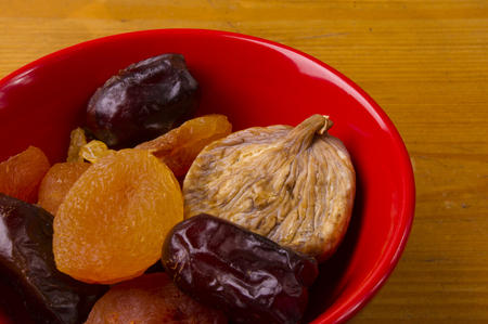 various dried fruits in red plate on wooden backgroundの写真素材